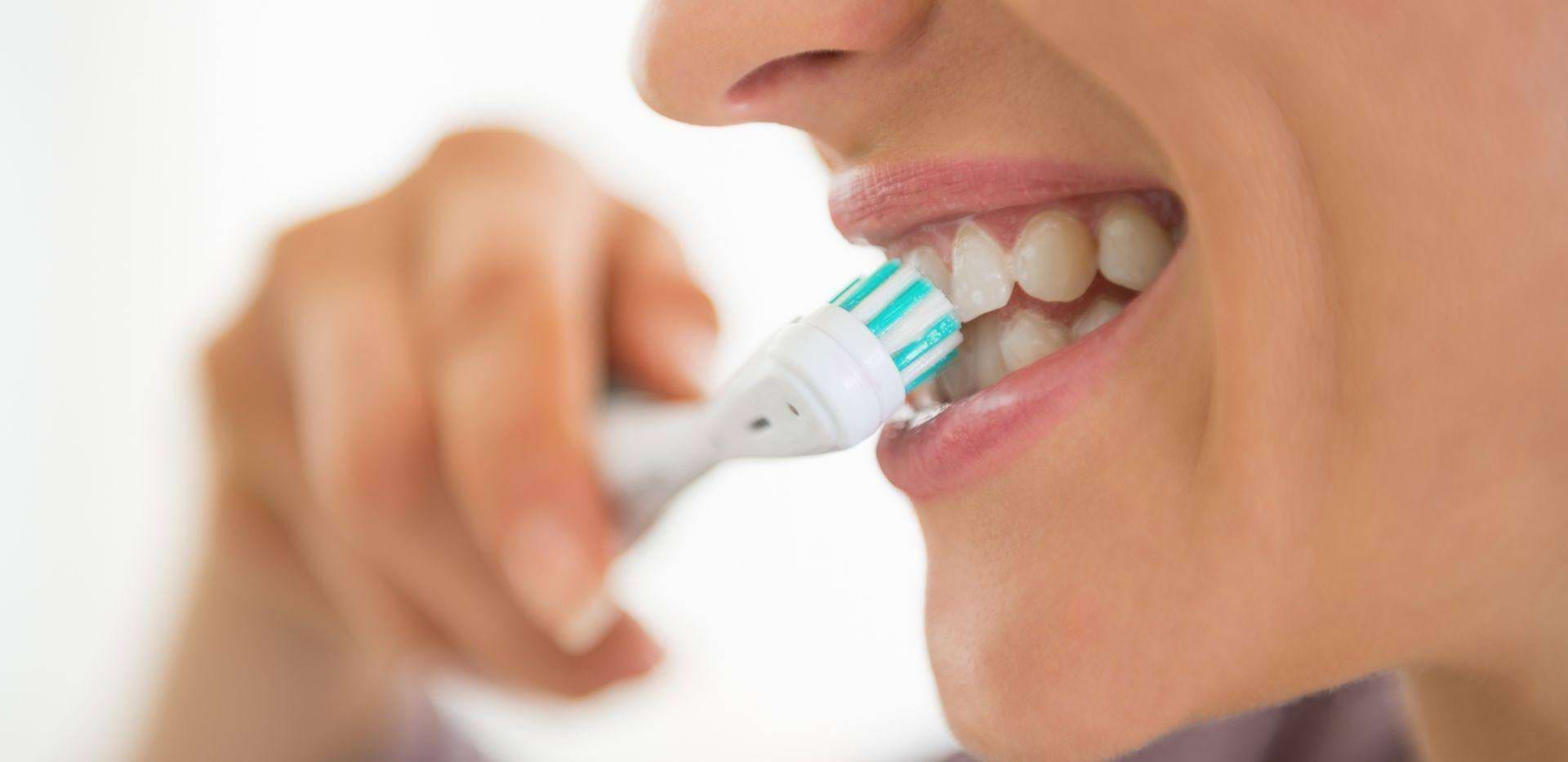 Čištění zubů zubním kartáčkem pro zdravou ústní hygienu.
