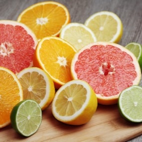 Různé druhy nakrájeného citrusového ovoce na dřevěné desce.
