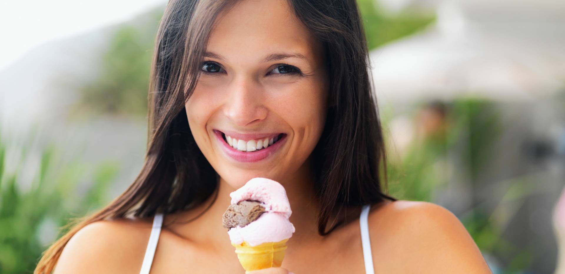 Žena se širokým úsměvem drží zmrzlinu.