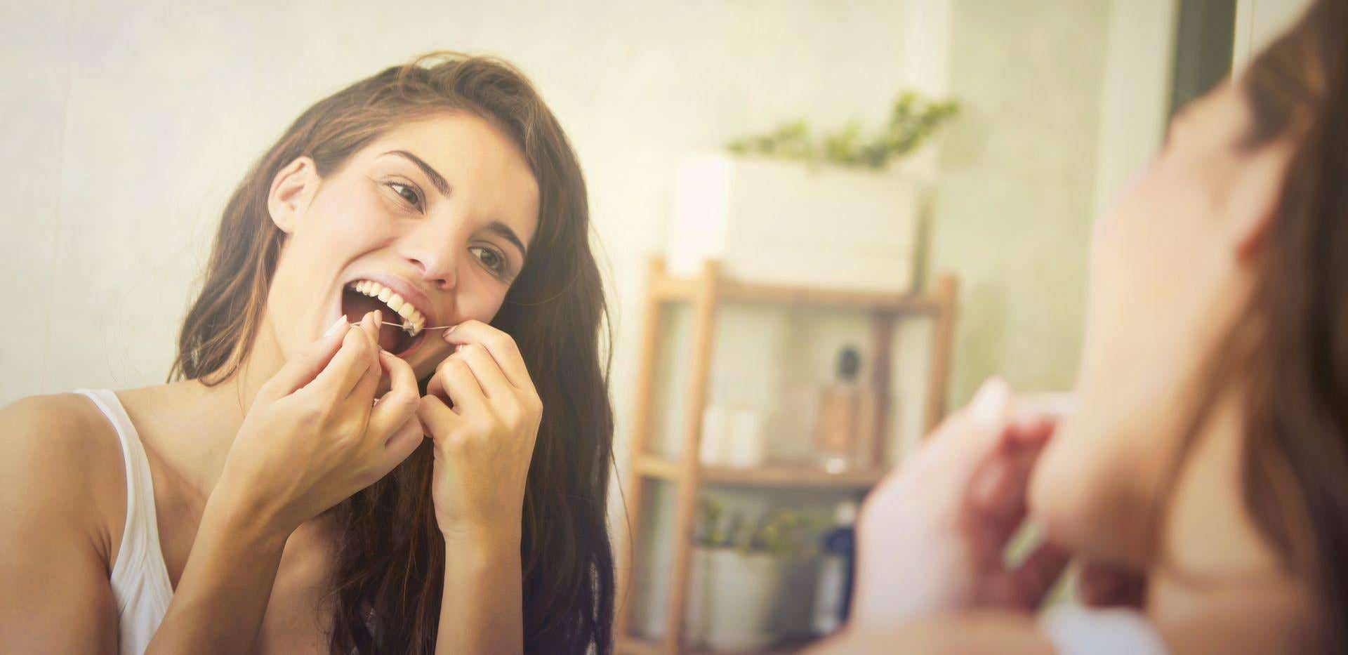 Mladá žena používá zubní nit