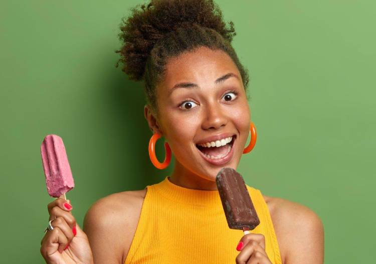 Úsměvavá žena drží dva nanuky.