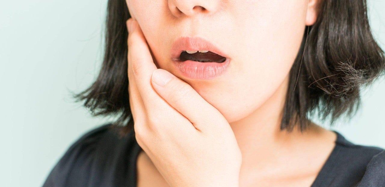 Žena si zakrývá obličej a jeví známky bolesti