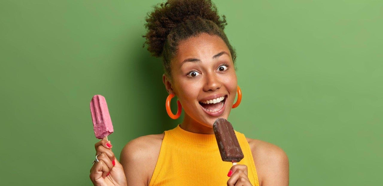 Žena se širokým úsměvem držící dva různé nanuky