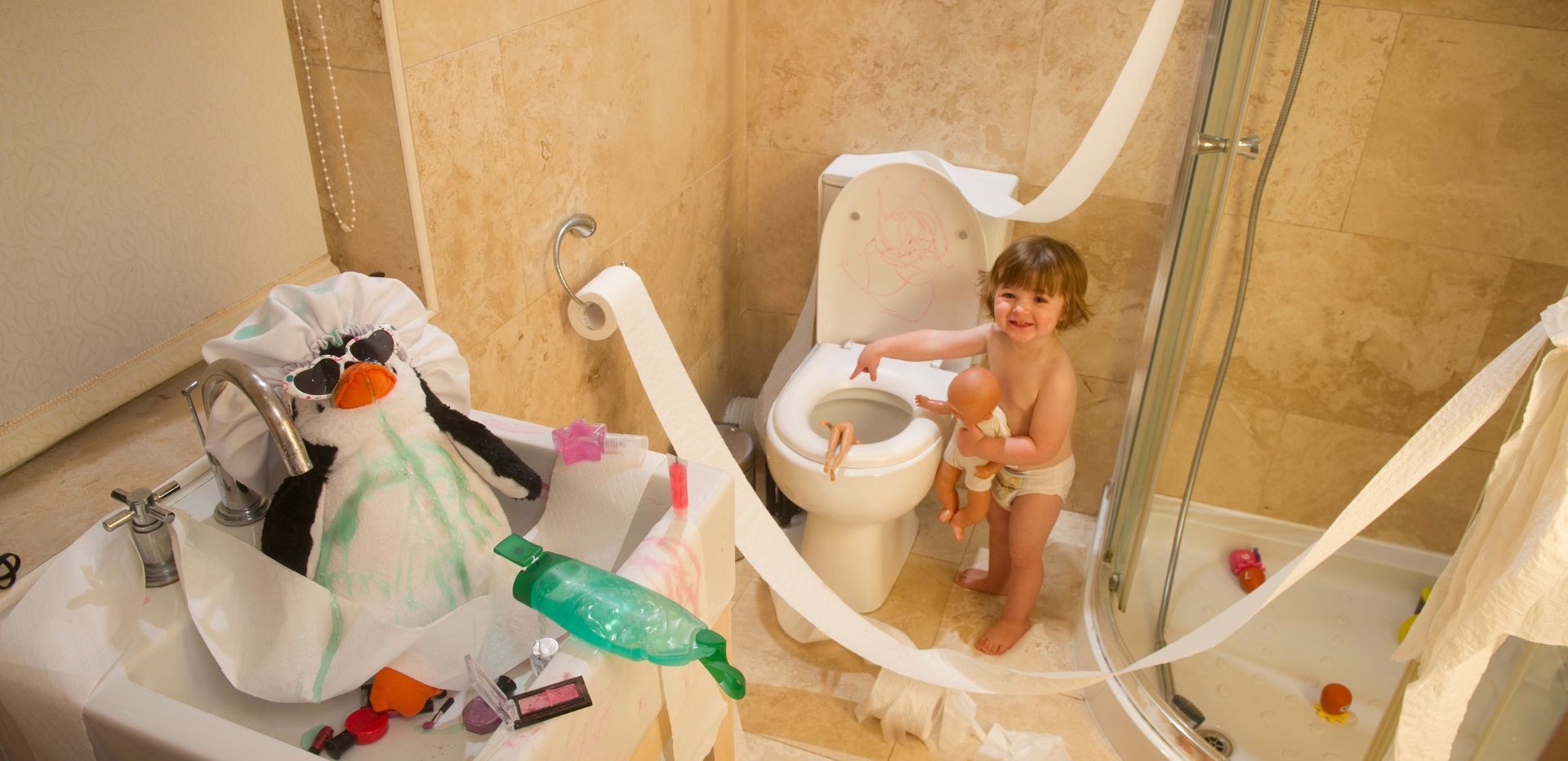 Malé dítě hrající si v koupelně s toaletním papírem.