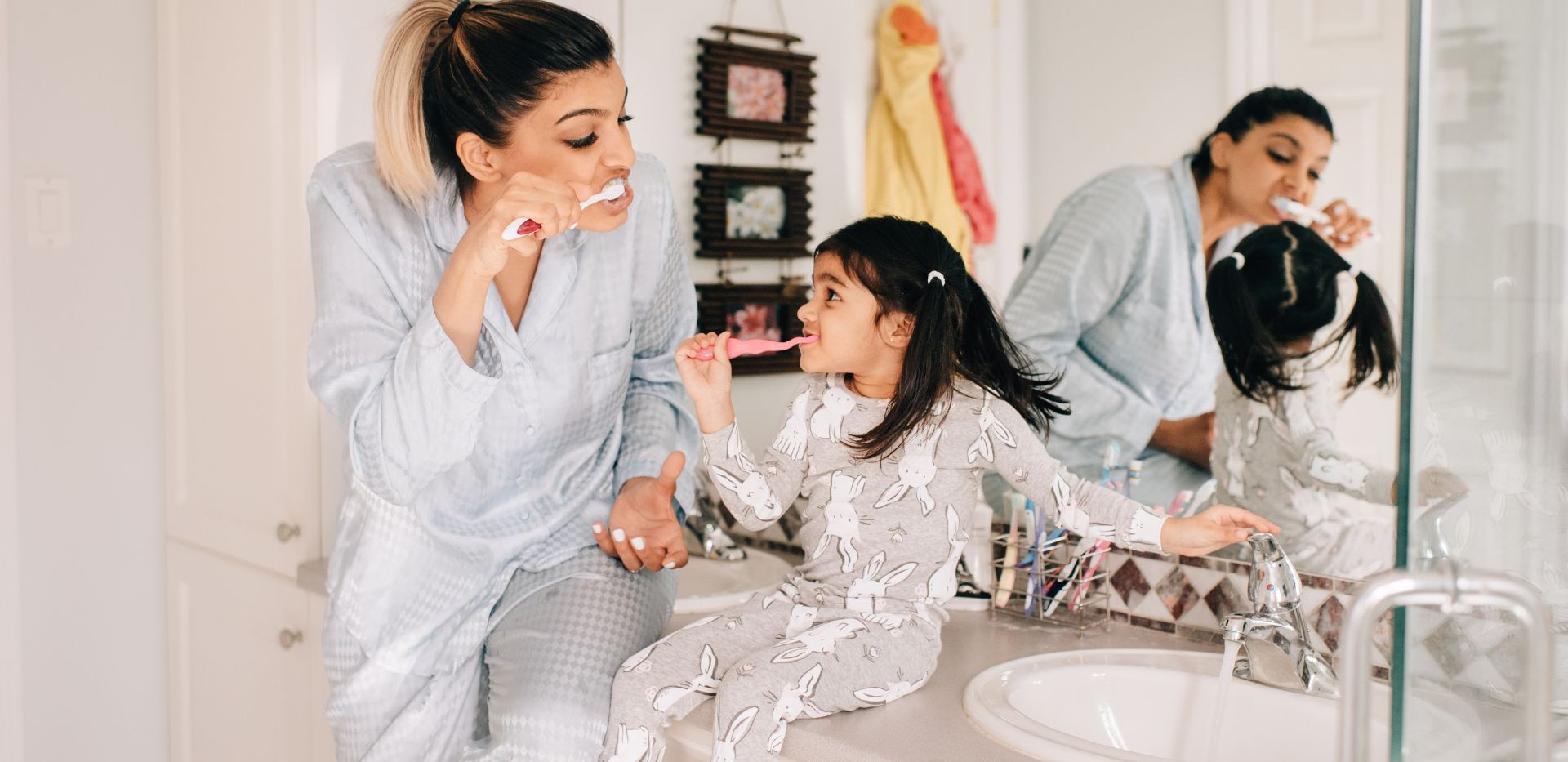 Matka a dítě si společně čistí zuby v koupelně.