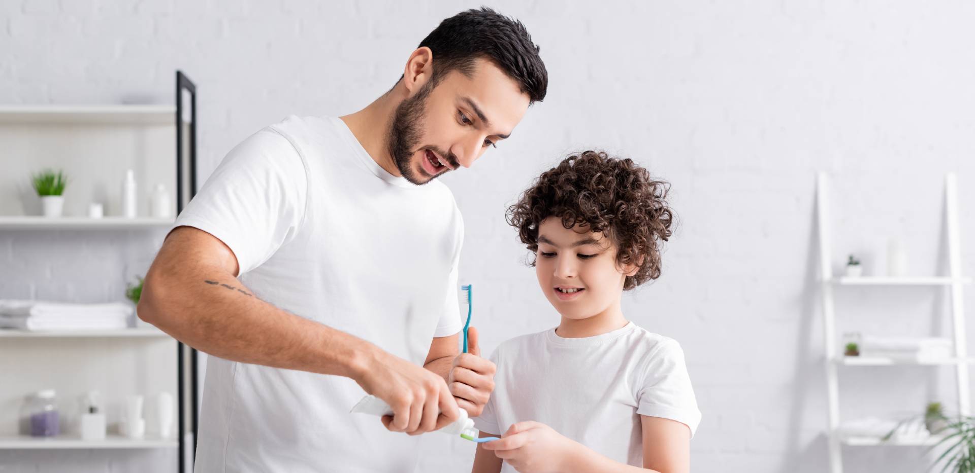 Muž a chlapec nanášejí zubní pastu na zubní kartáčky.
